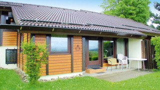 Chalet i ferielandsbyen Öfingen, 68 kvm Type C Sioux, træfacade, terrasse med stole og bord.