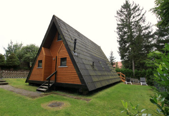 Foto eines dreieckigen Holzhauses namens 'Type A1 - Nurdachhaus' mit Rasenfläche in Deutschland.
