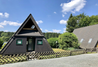 A-vormig houten lodgehuis met groene ramen en tuin, gefotografeerd bij een lodge in Duitsland.