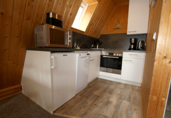 Cucina completamente attrezzata in una baita di legno con microonde, forno, caffettiera e lavastoviglie.
