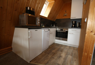 Fully equipped kitchen in a wooden lodge, with microwave, oven, coffee maker and dishwasher in Germany.