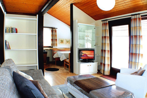 Soggiorno nel villaggio turistico Öfingen in Germania, arredo moderno, soffitto in legno e grandi finestre.