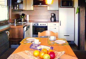 Zona cucina e pranzo accogliente in uno chalet con fruttiera e piatti apparecchiati sul tavolo.