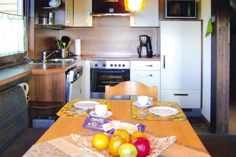 Zona cucina e pranzo accogliente in uno chalet con fruttiera e piatti apparecchiati sul tavolo.