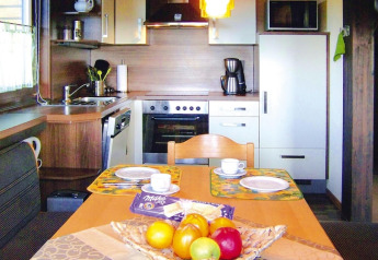Cozy kitchen and dining area in a chalet with wooden accents, fruit bowl, and set dining plates.