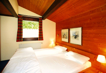 Slaapkamer met houten wanden en twee bedden in vakantiepark Öfingen, 68 m², Type C Sioux, Duitsland