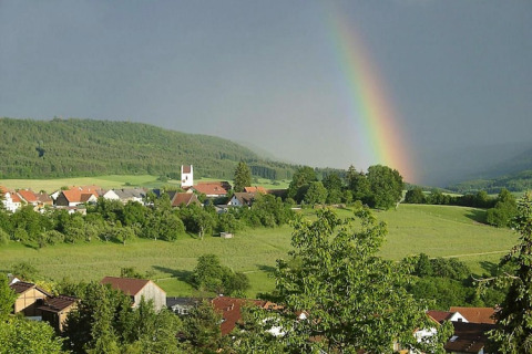 Arc-en-ciel sur collines et village vu du Holiday village «Öfingen - 68 sqm Type C Sioux» en Allemagne.