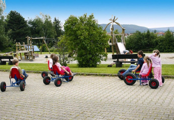 Des enfants sur des karts à pédales près d’une aire de jeux au Holiday village «Öfingen - 68 sqm Type C Sioux» en Allemagne.
