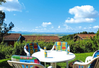 Table extérieure avec chaises colorées, vue sur toits et campagne au village vacances Öfingen en Allemagne.