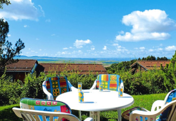 Outdoor table with colorful chairs overlooking scenic rooftops and countryside at Holiday village Öfingen, Germany.