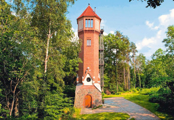 Water tower 75 sqm chalet tussen groene bomen, met een blauwe hemel, in een rustige bosrijke omgeving.