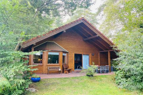Holiday home Svenja Wiefelstede-Lehe, a wooden lodge with terrace seating set amidst lush greenery.