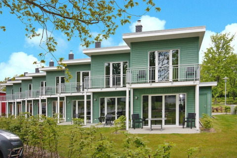 Groene terraswoningen met balkon en tuinmeubilair bij Ostseeresort Dampland op een zonnige dag