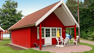 Rødt sommerhus i Holiday park Markgrafenheide Warnemünde Type 1 med terrasse og havemøbler.