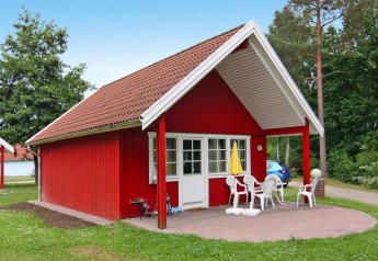 Rødt sommerhus i Holiday park Markgrafenheide Warnemünde Type 1 med terrasse og havemøbler.