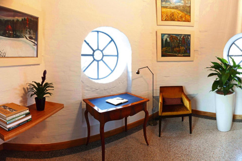Cozy corner in Water tower 75 sqm chalet, Germany, with round windows, plants, and colorful artworks.