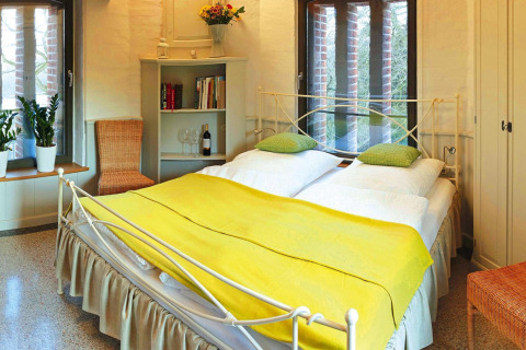 Cozy bedroom in chalet 'Water tower 75 sqm' in Germany featuring a double bed and bright decor.