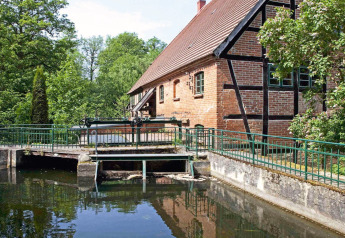 Afbeelding van chalet 'Water tower 75 sqm' aan een kanaal met bakstenen huis en bomen in Duitsland.