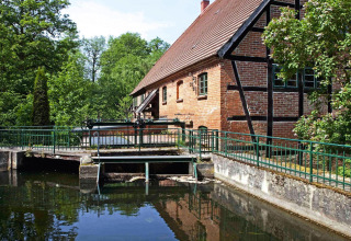 Billede af chaleten 'Water tower 75 sqm' ved en kanal med grønne træer og rød murstensbygning i Tyskland.