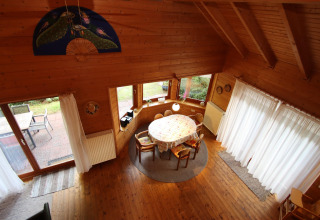 Overhead view of dining area at Holiday home Svenja Wiefelstede-Lehe in Germany with wood interior and windows.