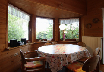 Comedor rústico con paredes de madera y ventanales al bosque en Holiday home Svenja Wiefelstede-Lehe.