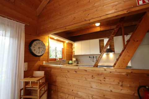 Wood-paneled kitchen and dining area at Holiday home Svenja Wiefelstede-Lehe, Germany, with clock on wall.