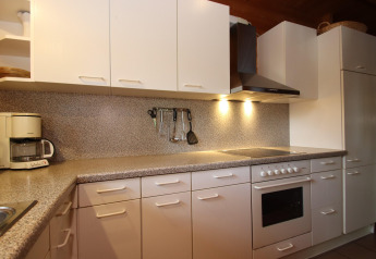 Cocina moderna con armarios blancos, electrodomésticos y encimera gris en Holiday home Svenja Wiefelstede-Lehe.