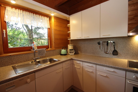 Cozy kitchen with white cabinets, window view of trees, appliances at Holiday home Svenja, Germany.