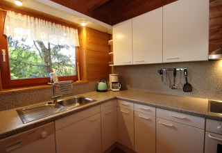 Cozy kitchen with white cabinets, window view of trees, appliances at Holiday home Svenja, Germany.