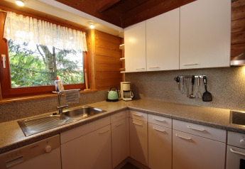 Acogedora cocina con armarios blancos, ventana, electrodomésticos y vista a árboles en Casa Svenja.