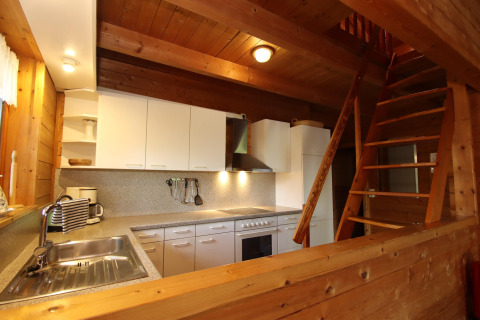 Wood-paneled kitchen with white cabinets and staircase at Holiday home Svenja Wiefelstede-Lehe, Germany.