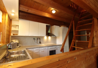Wood-paneled kitchen with white cabinets and staircase at Holiday home Svenja Wiefelstede-Lehe, Germany.