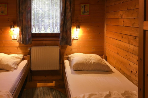Knusse houten kamer met twee eenpersoonsbedden, raam en verlichting in Holiday home Svenja, Duitsland.
