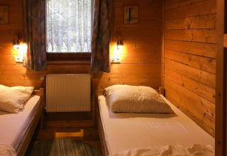 Habitación revestida de madera con dos camas individuales, ventana y luz reconfortante en Holiday home Svenja.