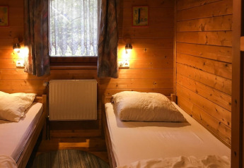 Habitación revestida de madera con dos camas individuales, ventana y luz reconfortante en Holiday home Svenja.
