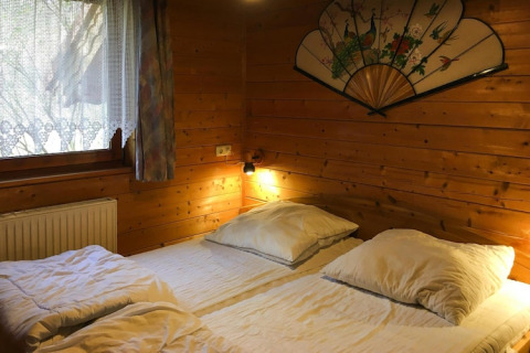 Dormitorio rústico de madera con dos camas y abanico decorativo en Holiday home Svenja Wiefelstede-Lehe, Alemania.