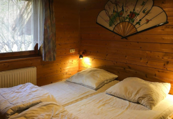 Dormitorio rústico de madera con dos camas y abanico decorativo en Holiday home Svenja Wiefelstede-Lehe, Alemania.