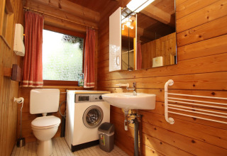 Houten badkamer met wasmachine, toilet en lavabo in Holiday home Svenja Wiefelstede-Lehe, Duitsland.