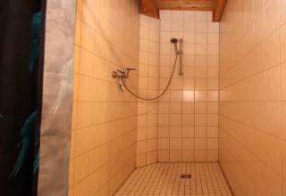 Shower with light tiles and a handheld showerhead at Holiday home Svenja Wiefelstede-Lehe, Germany.