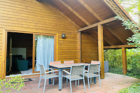 Outdoor dining area at the wooden Holiday home «Svenja Wiefelstede-Lehe» lodge, surrounded by nature in Germany.