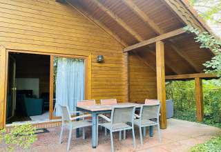 Buitenterras bij houten lodge Holiday home «Svenja Wiefelstede-Lehe», omgeven door groen in Duitsland.