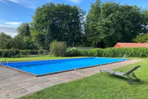 Buitenzwembad met ligstoel en groene tuin bij Type C House 363-364 in Duitsland.