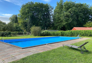 Outdoor swimming pool with a lounge chair and green surroundings at Type C House 363-364, Germany.