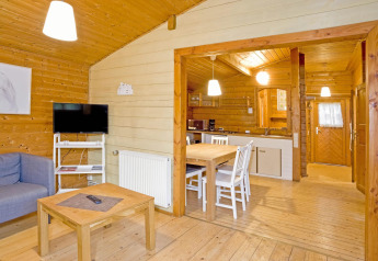 Interior de madera de la cabaña Type C House 363 364 361 362 en Alemania con cocina, mesa y sofá.