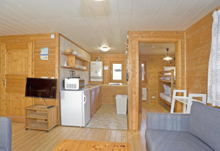 Interior of Type C House lodge with wooden walls, kitchen, bunk bedroom, and TV living area.