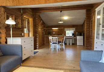 Interior luminoso y acogedor de cabaña con vigas de madera, comedor y cocina abierta en una casa en Alemania.