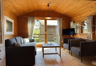 Houten woonkamer in een Duits lodge met sofa’s, tv, salontafel en uitzicht op het terras.