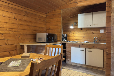 Wood-paneled kitchen and dining area in a lodge, featuring a microwave, coffeemaker and dining table.