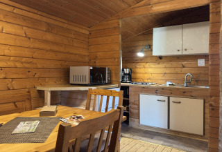 Wood-paneled kitchen and dining area in a lodge, featuring a microwave, coffeemaker and dining table.