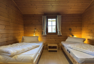 Houten kamer met twee eenpersoonsbedden, centraal raam en nachtkastjes in Type C House in Duitsland